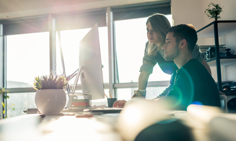 man and woman looking at computer monitor